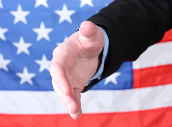 Empresario dando la mano por un apretón de manos en el fondo de la bandera estadounidense —  Fotos de Stock