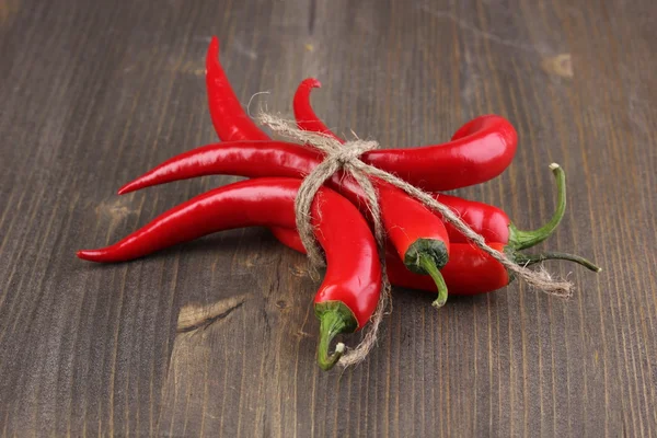 stock image Red hot chili peppers tied with rope on wooden background