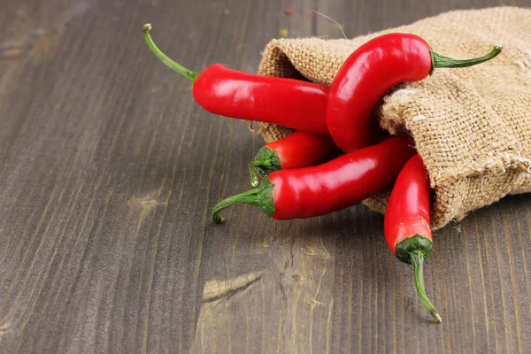 Red hot chili papričky v sáčku na dřevěné pozadí — Stock fotografie