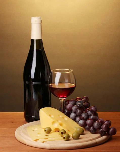 Garrafa de grande vinho com vinho e queijo em mesa de madeira sobre fundo marrom — Fotografia de Stock