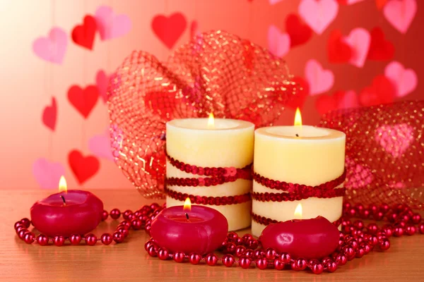 Beautiful candles with romantic decor on a wooden table on a red background Stock Image