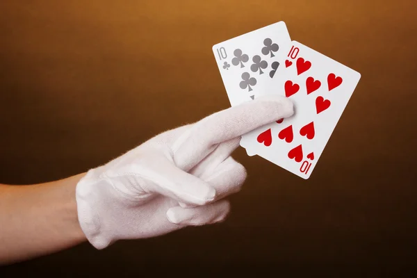 Cards in hand on brown background — Stock Photo, Image