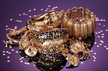 Beautiful golden jewelry on purple background clipart