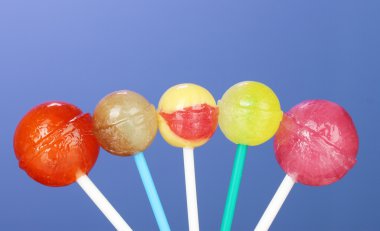 Bright and delicious lollipops on dark blue background close-up clipart