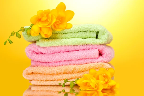 Πολύχρωμο πετσέτες και λουλούδια σε κίτρινο φόντο — Φωτογραφία Αρχείου