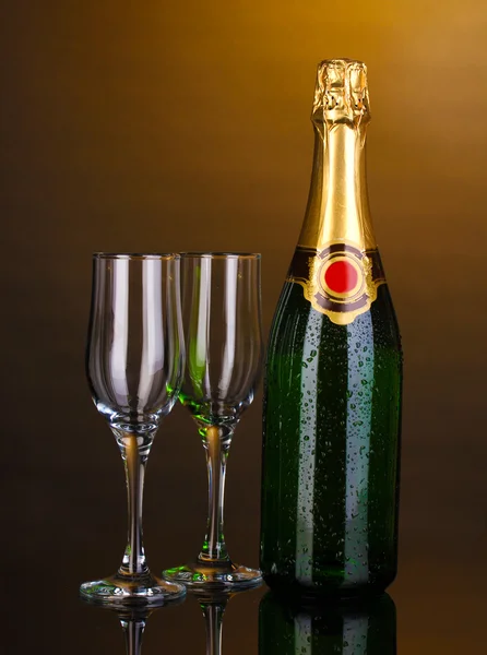 Butelka szampana i puchary na brązowym tle — Zdjęcie stockowe