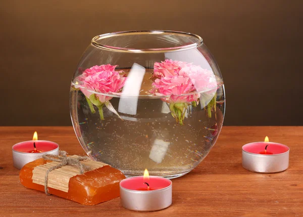 Спа композиция свечей, мыла и розовых роз, плавающих на деревянном фоне — стоковое фото