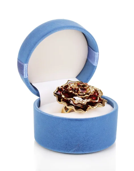 Золотое кольцо с большим красным цветком и прозрачные кристаллы в синей бархатной коробке изолированы на белом — стоковое фото