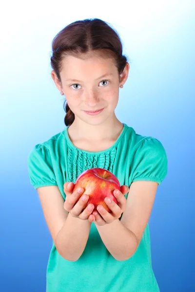 Retrato de niña hermosa con manzana sobre fondo azul — Foto de Stock