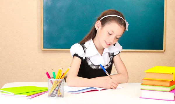 Little schoolchild in classroom write in notebook — Stock Photo, Image