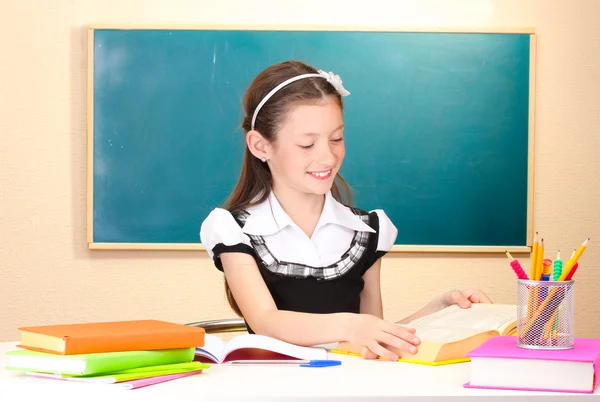 Little schoolchild in classroom write in notebook blackboard — Stock Photo, Image