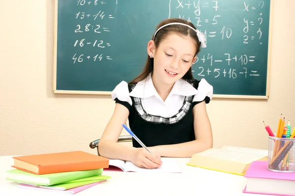 Mały uczeń/uczennica w klasie napisać w notatniku — Zdjęcie stockowe