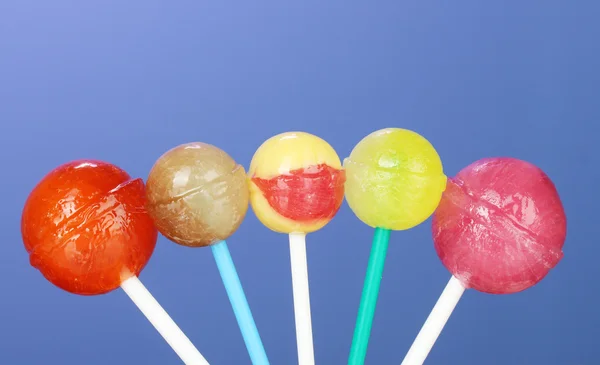 Lollipops brilhantes e deliciosos no fundo azul escuro close-up — Fotografia de Stock