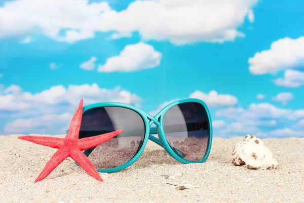 Elegantes gafas de sol de mujer con estrella de mar y concha en la playa —  Fotos de Stock