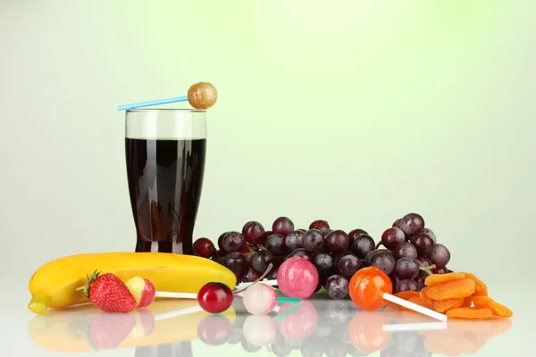 A composição dos pirulitos, frutas e um copo de cola isolado em branco — Fotografia de Stock