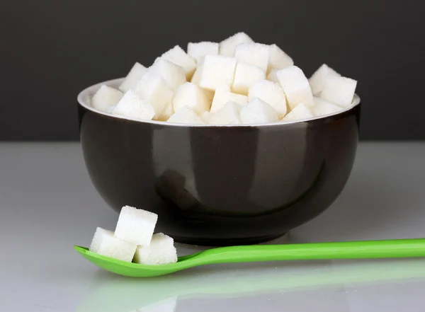 Tigela preta com açúcar de caroço branco com colher colorida em fundo cinza close-up — Fotografia de Stock