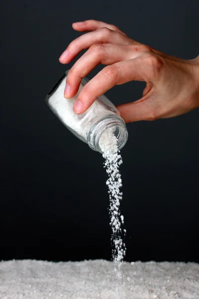 Womans hand holding the salt shaker on grey background close-up — Stock Photo, Image