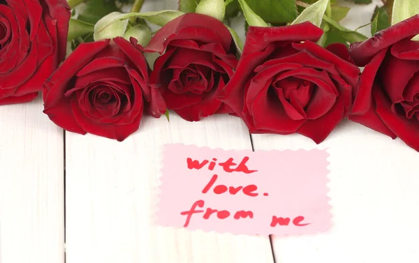 흰색 나무 테이블 클로즈업 메모와 함께 빨간 장미 꽃다발 — 스톡 사진