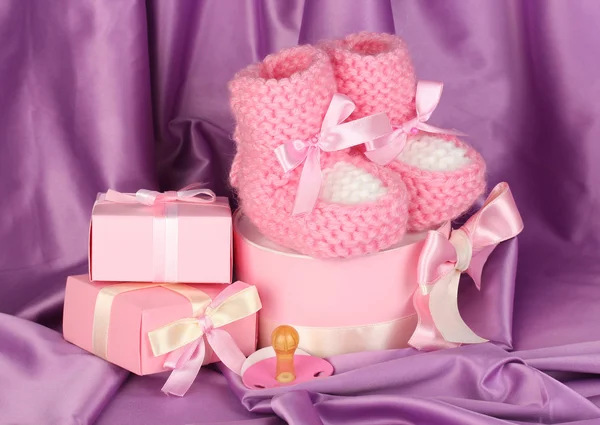 Botas de bebé rosa, chupete, regalos sobre fondo de seda —  Fotos de Stock