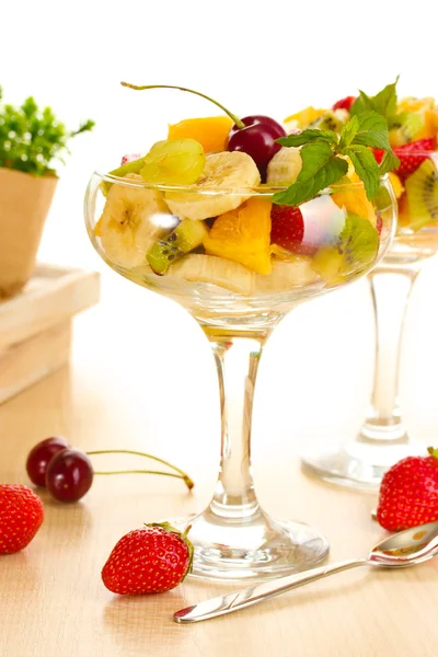 Färsk fruktsallad och jordgubbar på träbord — Stockfoto