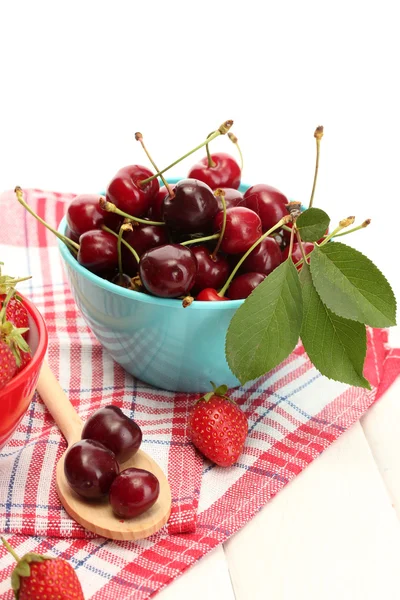 Спелые клубника и ягоды вишни в мисках на белом деревянном столе — стоковое фото