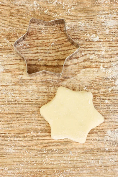 Schaar voor het deeg aan de ongebakken koekjes op een houten tafel close-up — Stockfoto