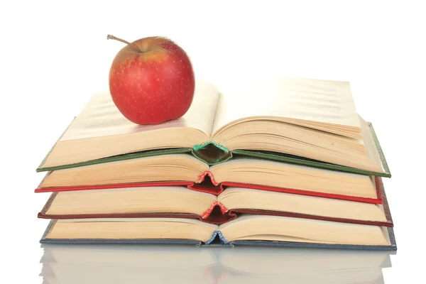 Pila di libri aperti con mela isolata su bianco — Foto Stock