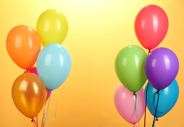 Bunte Luftballons auf gelbem Hintergrund in Nahaufnahme — Stockfoto