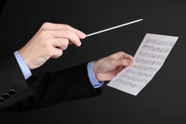 Mãos de maestro de música com bastão e notas isoladas em preto — Fotografia de Stock