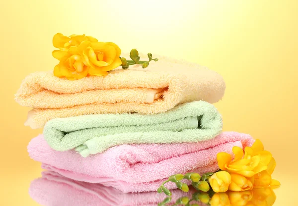Colorful towels and flowers on yellow background Stock Picture