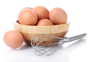 ahşap kase üzerinde beyaz izole kahverengi yumurta ve yumurta çırpma için metal çırpma teli