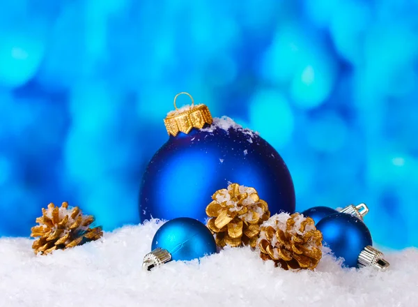 Hermosas bolas de Navidad azul y conos en la nieve sobre fondo azul — Foto de Stock