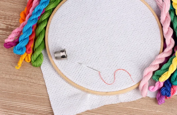 The embroidery hoop with canvas and bright sewing threads for embroidery in the table — Stock Photo, Image