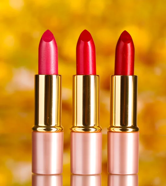 Hermosos lápices labiales rojos sobre fondo amarillo —  Fotos de Stock