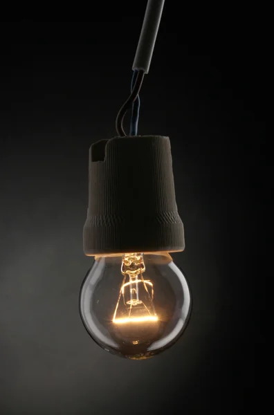 En tänd glödlampa på svart bakgrund — Stockfoto
