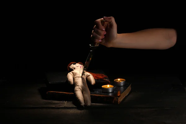Voodoo docka flicka genomborrad av kniv på ett träbord i levande ljus — Stockfoto