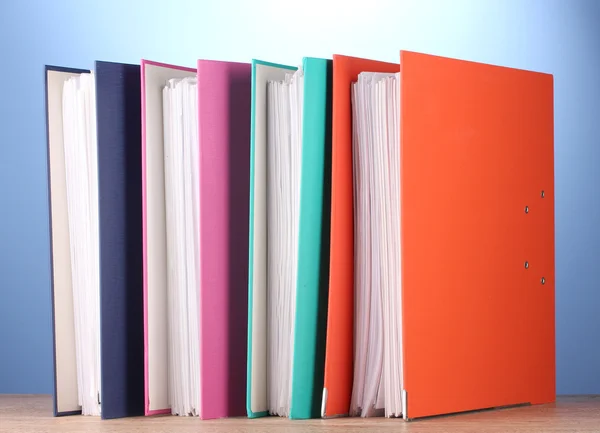 Bright office folders on wooden table on blue background — Stock Photo, Image
