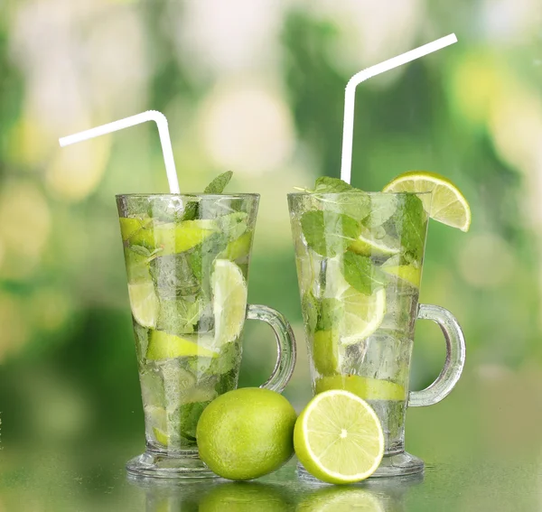 Glasses of cocktail with lime and mint on green background — Stock Photo, Image