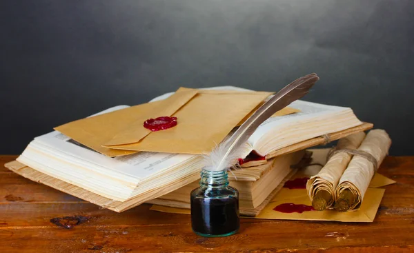 Oude boeken, rollen, veer pen en inktpotje op houten tafel op grijze achtergrond — Stockfoto