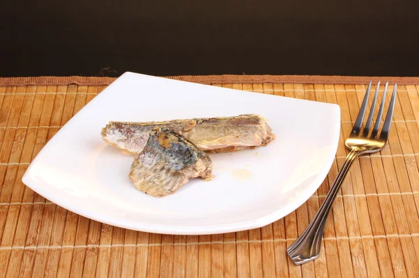 stock image Tasty mackerel on plate on wooden mat on brown background