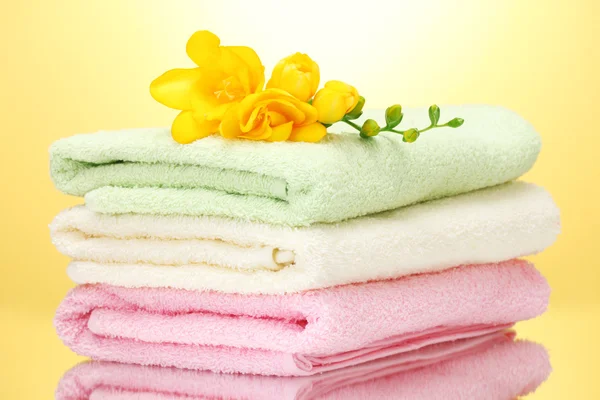 Färgglada handdukar och blommor på gul bakgrund — Stockfoto
