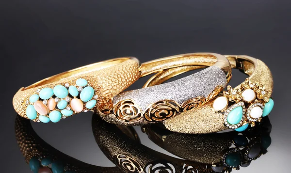 Piękne złote bransoletki na szarym tle — Zdjęcie stockowe
