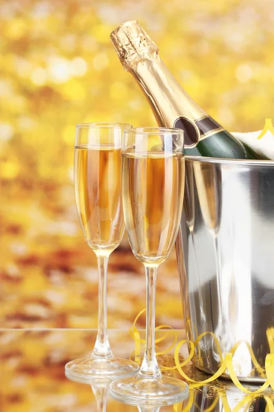 Láhev šampaňského v kbelík s ledem a sklenic šampaňského, na žlutém podkladu — Stock fotografie