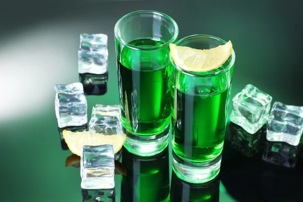 Dois copos de absinto, limão e gelo no fundo verde — Fotografia de Stock