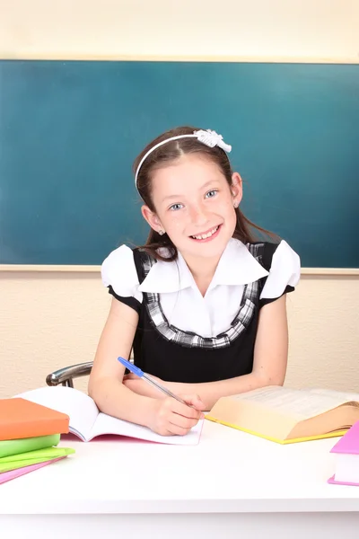 Little schoolchild in classroom write in notebook — Stock Photo, Image