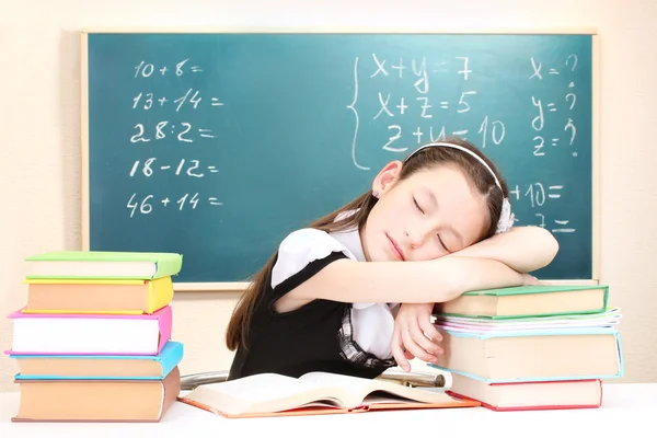 Liten skolflicka sover i klassrum nära blackboard — Stockfoto