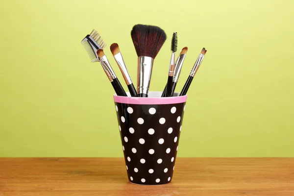 Makeup borstar i en svart polka-dot kopp på gul bakgrund — Stockfoto
