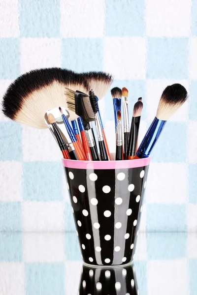 Makeup borstar i en svart polka-dot kopp på färgstarka bakgrund — Stockfoto