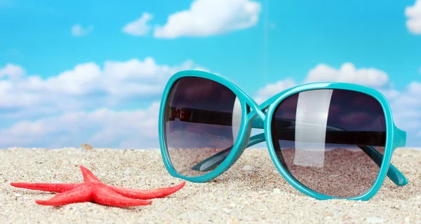 Elegantes gafas de sol de mujer con estrellas de mar en la playa —  Fotos de Stock