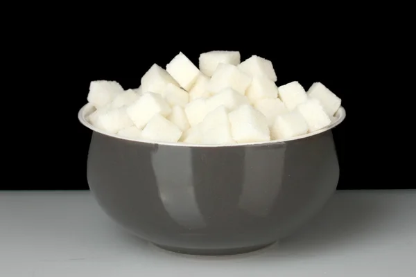 Cukier biały guzek w misce na czarnym tle — Zdjęcie stockowe